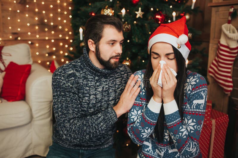 Feliz Navidad y Feliz Año Nuevo Pares jovenes que celebran día de fiesta en casa Mujer joven con el pañuelo Muchacha enferma imagenes de archivo Feliz Navidad y Feliz Año Nuevo Pares jovenes que celebran día de fiesta en casa Mujer joven con el pañuelo Muchacha enferma imagenes de archivo