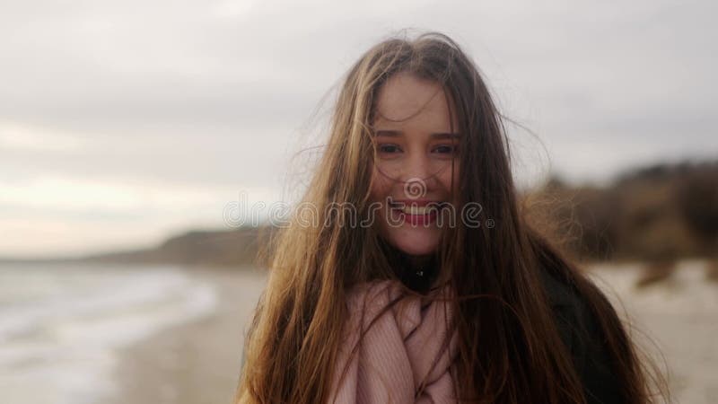 Feliz niña de etnia mixta sonriendo y mirando la cámara a la orilla del mar. retrato de una encantadora y alegre mujer asiática ri