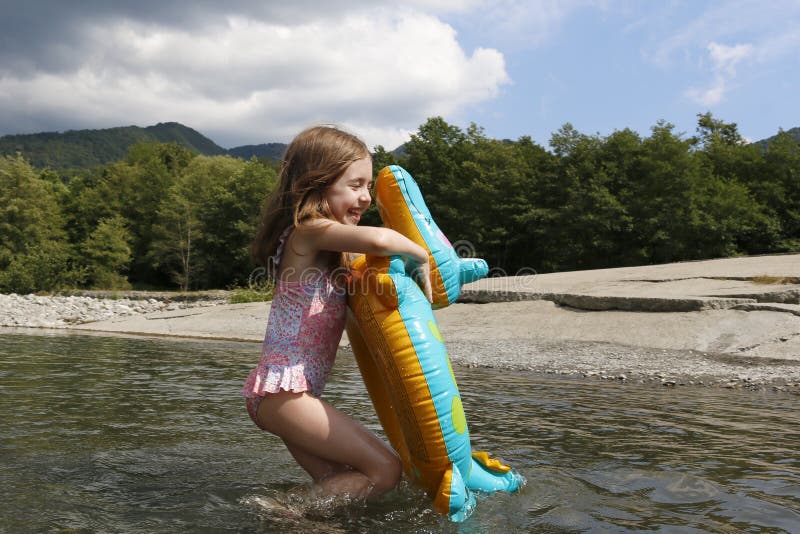 Feliz niña risible disfrutando nadando en el río con cocodrilo de anillo de goma fotos de archivo