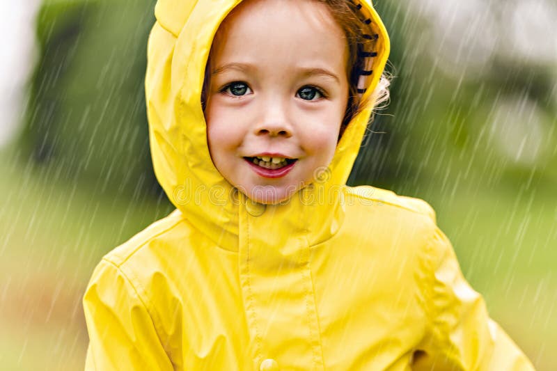 Feliz niño gracioso con impermeable bajo el día de lluvia de verano foto de archivo libre de regalías