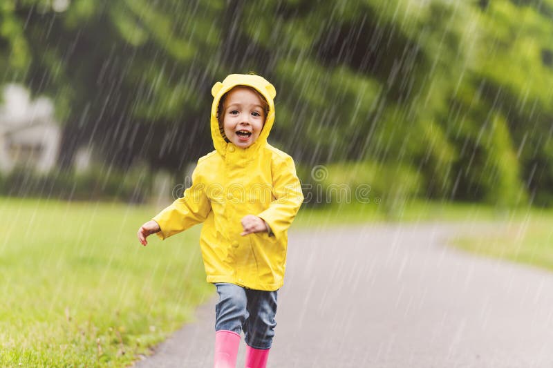 Feliz niño gracioso con impermeable bajo el día de lluvia de verano fotografía de archivo libre de regalías