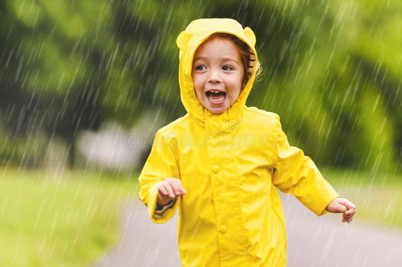 Feliz niño gracioso con impermeable bajo el día de lluvia de verano fotografía de archivo