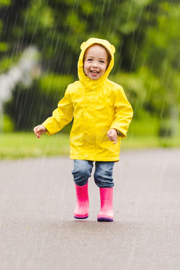 Feliz niño gracioso con impermeable bajo el día de lluvia de verano imagen de archivo