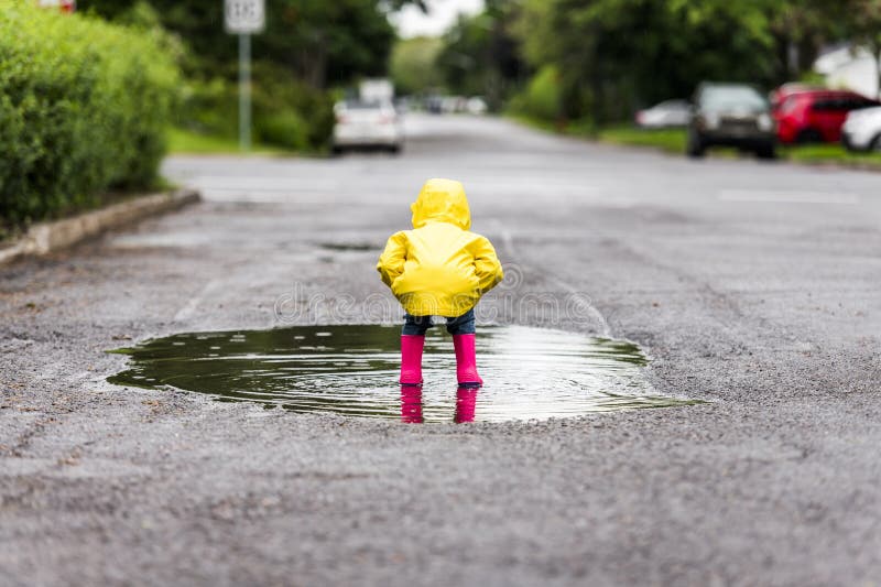 Feliz niño gracioso con impermeable bajo el día de lluvia de verano foto de archivo libre de regalías