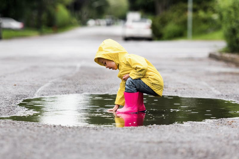Feliz niño gracioso con impermeable bajo el día de lluvia de verano foto de archivo