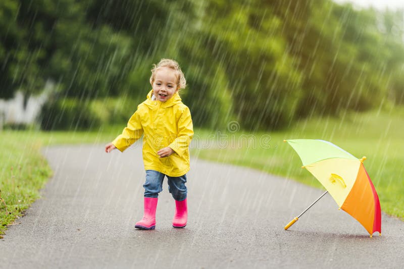 Feliz niño gracioso con paraguas multicolor bajo el día de lluvia de verano imagen de archivo libre de regalías