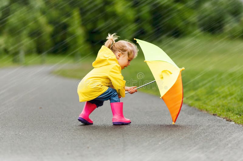 Feliz niño gracioso con paraguas multicolor bajo el día de lluvia de verano imagen de archivo libre de regalías