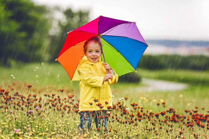 Feliz niño gracioso con paraguas multicolor bajo el día de lluvia de verano imagen de archivo