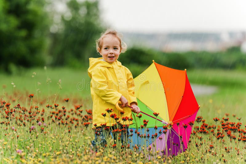 Feliz niño gracioso con paraguas multicolor bajo el día de lluvia de verano imagen de archivo