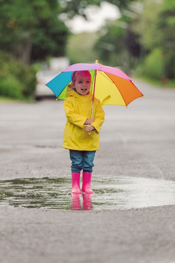 Feliz niño gracioso con paraguas multicolor bajo el día de lluvia de verano foto de archivo libre de regalías