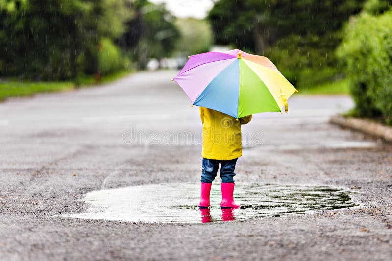 Feliz niño gracioso con paraguas multicolor bajo el día de lluvia de verano foto de archivo