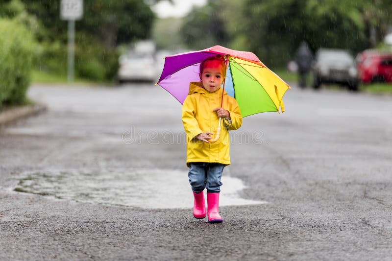 Feliz niño gracioso con paraguas multicolor bajo el día de lluvia de verano foto de archivo