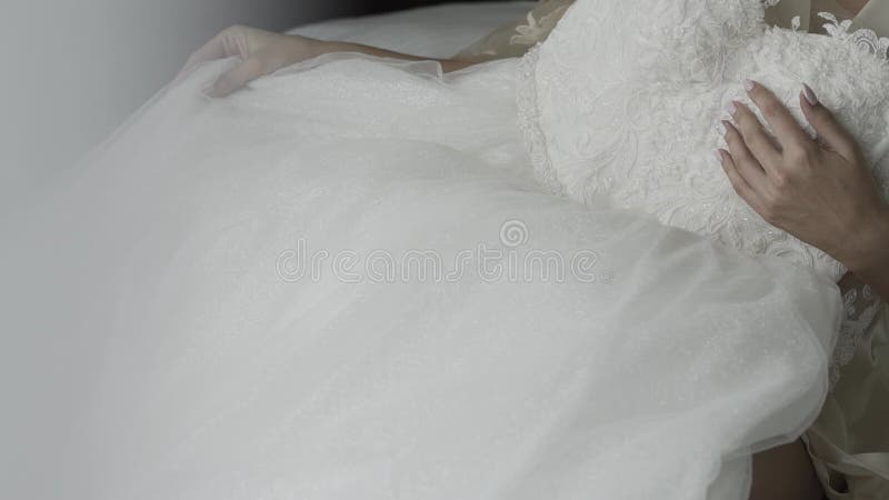 Feliz novia toca su vestido de boda con su mano