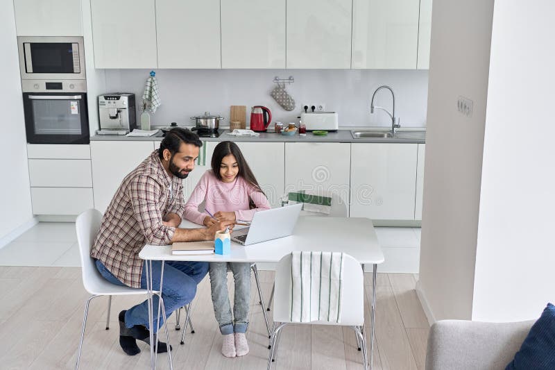 Feliz padre joven indio padre ayuda hija adolescente aprendizaje en casa. foto de archivo libre de regalías