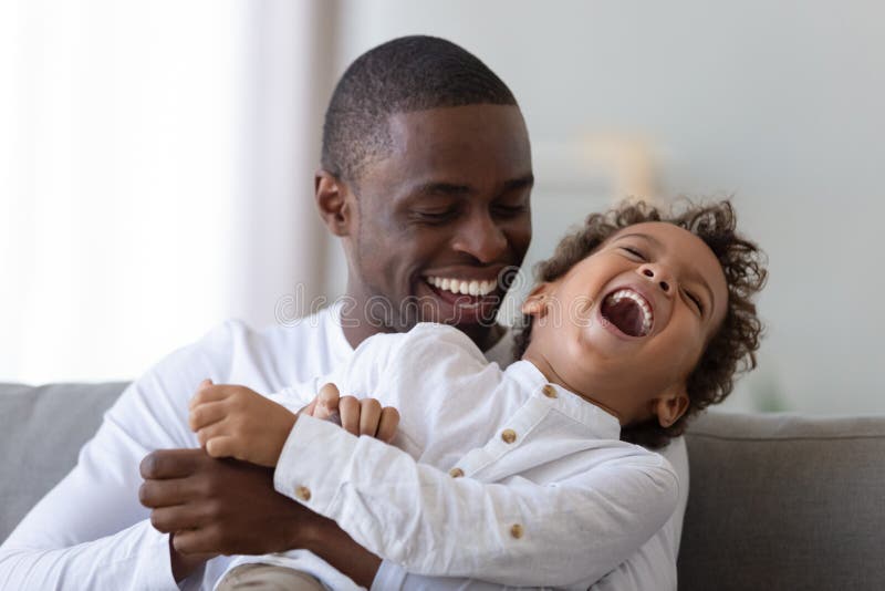 Feliz padre milenario afroamericano haciendo cosquillas de risa, hijo fotos de archivo libres de regalías