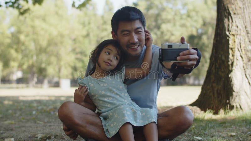 Feliz pai asiático tirando selfie com filha com câmera