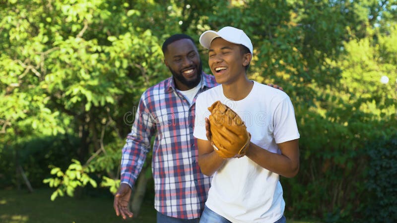 Feliz pai elogiando o filho jogando beisebol no parque, apoio familiar, conexão