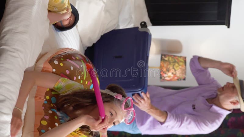 Feliz pareja familiar con dos niños desempacando en la habitación del hotel y divirtiéndose.