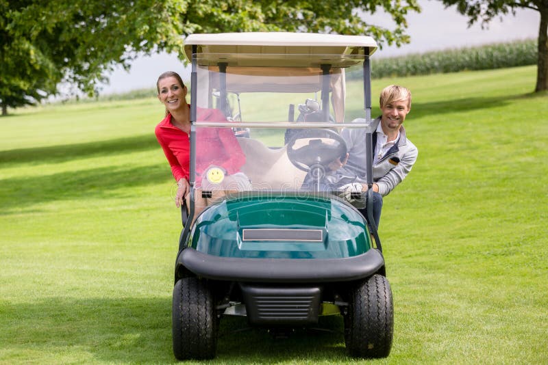 Feliz pareja sentada en el carrito de golf mirando imagenes de archivo Feliz pareja sentada en el carrito de golf mirando imagenes de archivo