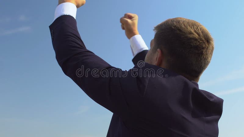 Feliz persona de negocios haciendo gestos de éxito y levantando la mano contra el paisaje