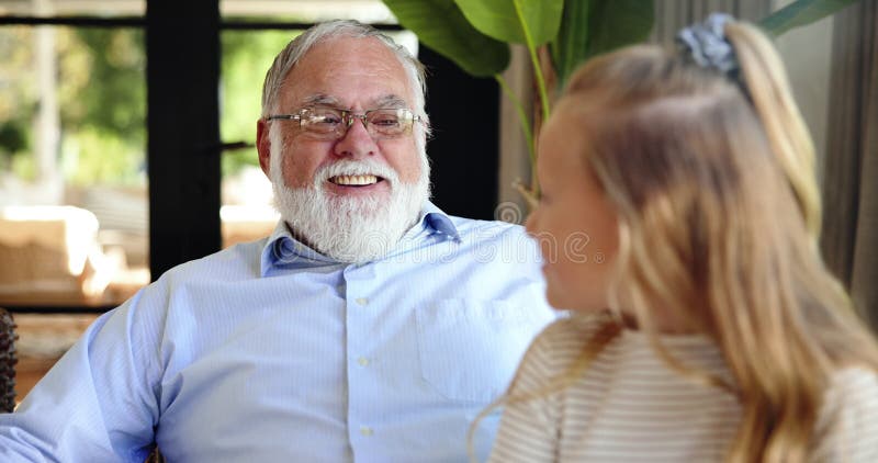 Feliz relajación y abuelo con un niño en casa con amor y tiempo familiar. La conversación sonriente y el veterano metrajes