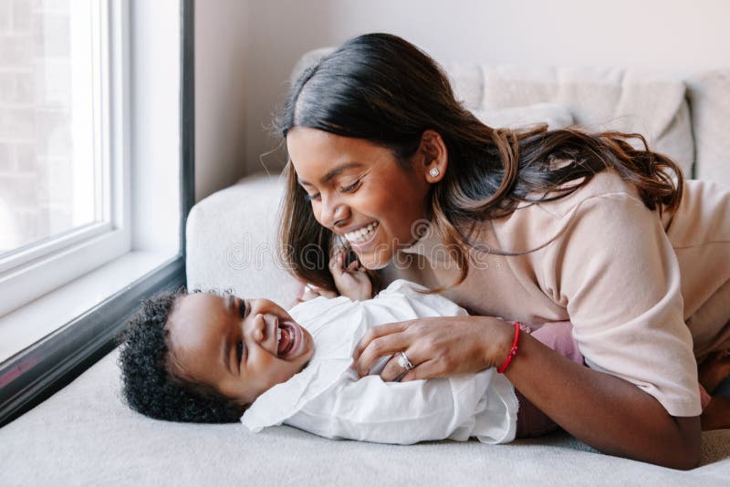 Feliz sonriendo madre india jugando con negro niña hija. familia mestiza gente mamá y un niño juntos imagenes de archivo