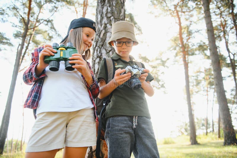 Feliz y emocionado colegio niños con mochilas con ropa informal disfrutando de caminar en el bosque el soleado día de otoño dos ac fotos de archivo libres de regalías