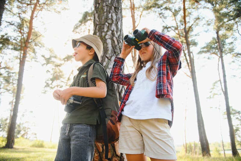Feliz y emocionado colegio niños con mochilas con ropa informal disfrutando de caminar en el bosque el soleado día de otoño dos ac foto de archivo libre de regalías