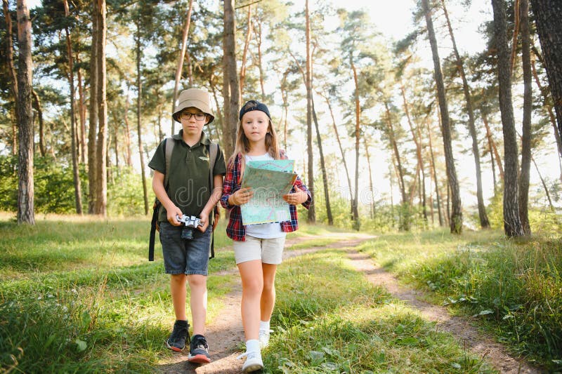 Feliz y emocionado colegio niños con mochilas con ropa informal disfrutando de caminar en el bosque el soleado día de otoño dos ac fotografía de archivo