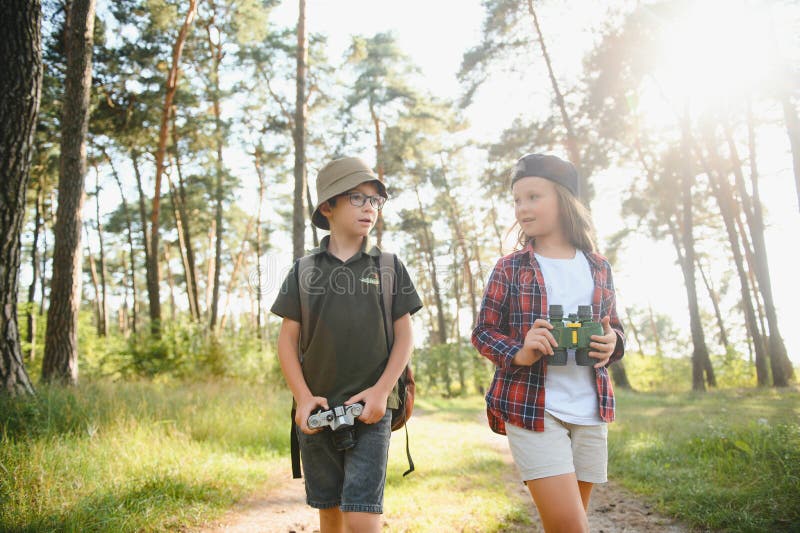 Feliz y emocionado colegio niños con mochilas con ropa informal disfrutando de caminar en el bosque el soleado día de otoño dos ac fotos de archivo libres de regalías