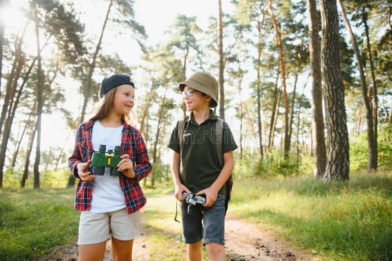 Feliz y emocionado colegio niños con mochilas con ropa informal disfrutando de caminar en el bosque el soleado día de otoño dos ac imagenes de archivo