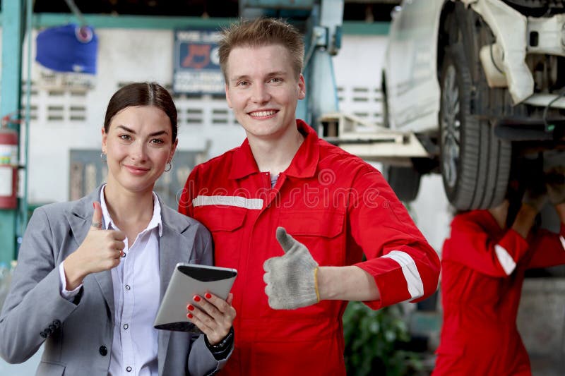Feliz y hermosa cliente mujer y hombre mecánico con uniforme rojo dando golpes. el cliente se siente satisfecho después del trabaj foto de archivo