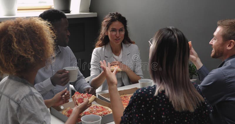 Feliz y relajado equipo multirracial de negocios, gente riéndose comiendo pizza de comida para llevar almacen de metraje de vídeo