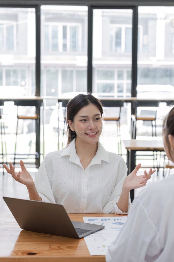 Female Accountant Discuss Financial Documents in Modern Office Setting with Natural Light and Laptops royalty free stock images