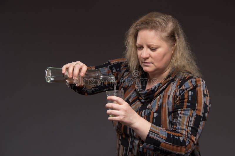 Female Alcoholism. Woman Aged One Drinks Vodka from a Bottle and Stock