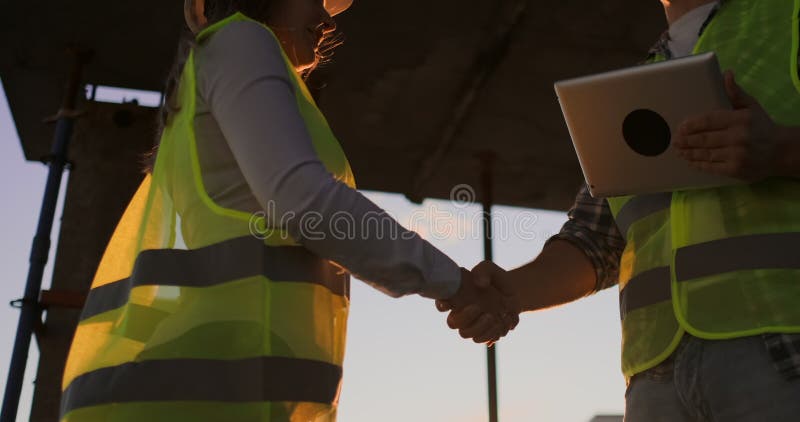 Female architect and construction worker shaking hands. Low angle view, copy space.