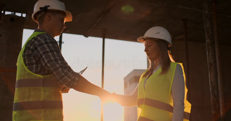 Female architect and construction worker shaking hands. Low angle view, copy space.