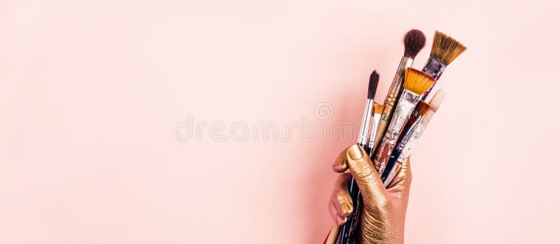 Female Artist golden hand with set of brushes. Banner format