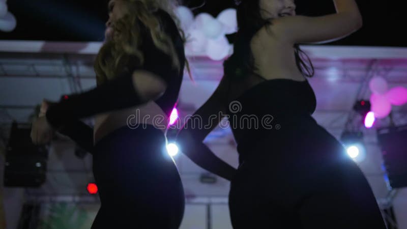 Female dancing in slow motion at night club, nightlife, women dancing at night party, close up two girls energy