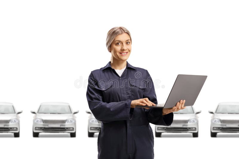 Female auto mechanic worker in a uniform holding a laptop computer in front of silver cars