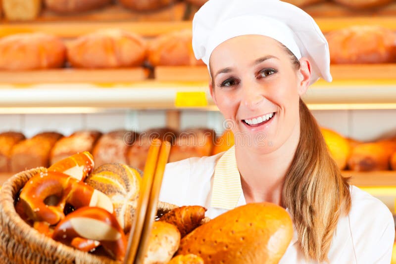 Ženské baker nebo prodavačka v jejím pekárna prodává čerstvý chléb, pečivo a pekárenské výrobky v košíku.