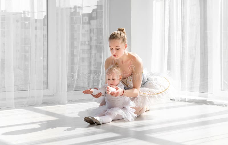 Female ballet dancer teaching little girl doing exarcises for stretching royalty free stock photo Female ballet dancer teaching little girl doing exarcises for stretching royalty free stock photo