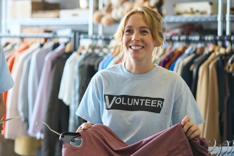 Female Charity Worker Checking Clothing Donations At Thrift Store. Charity sorting stock images, royalty-free photos and pictures