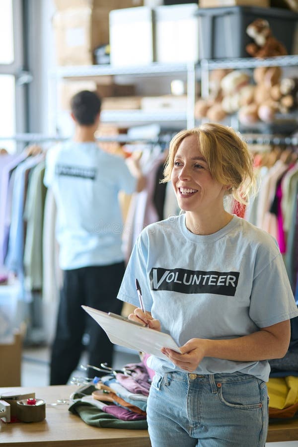 Female Charity Worker Checking Clothing Donations At Thrift Store. Charity sorting stock images, royalty-free photos and pictures