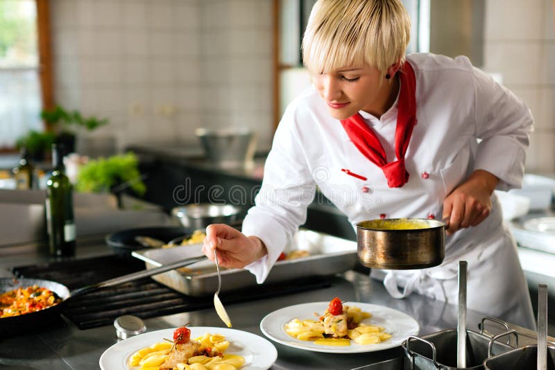 Una mujer cocinero en un restaurante o instalación que proporciona servicios de alojamiento La cocina cocinando excelente comida, ella es un decorando platos.