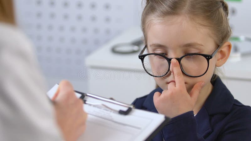 Female child looking at optometrist filling patient card, eyesight examination