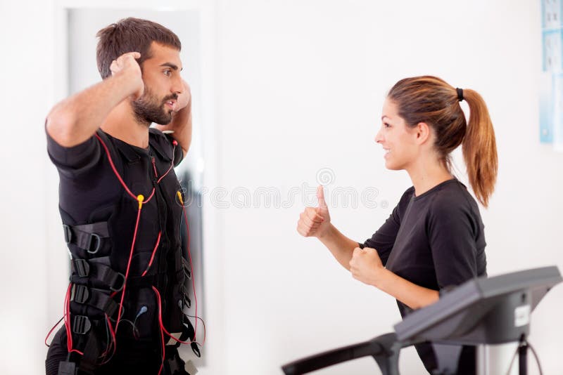 Female coach giving man ems electro muscular stimulation exerci