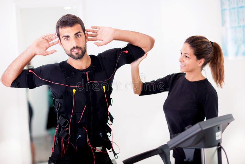 Female coach giving man ems electro muscular stimulation exerci