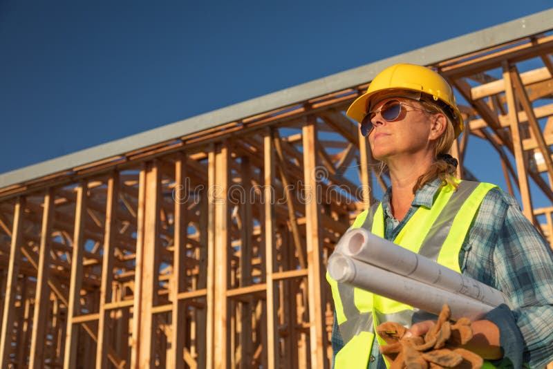 Female Construction Worker Holds Blueprints at Construciton Site stock images