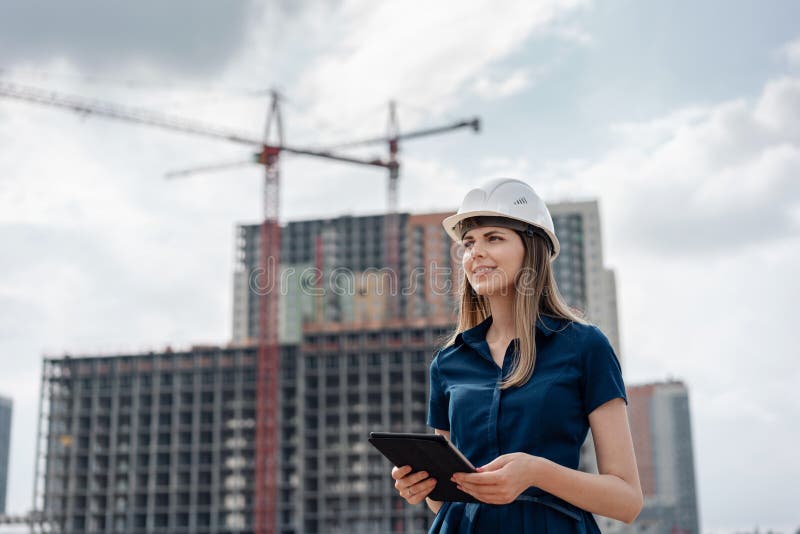 Female construction engineer. Architect with a tablet computer at a construction site. Young Woman looking, building stock images
